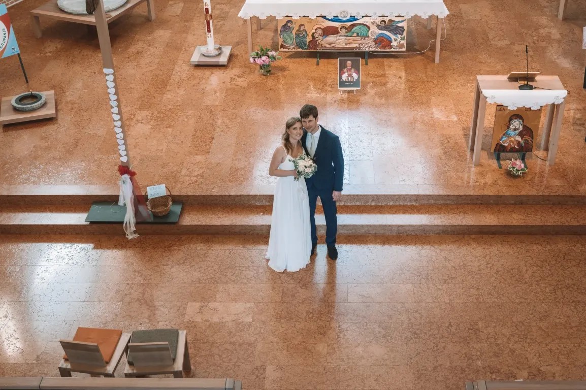 Poročna fotografija mladoporočencev; ujet pristen trenutek z naravno svetlobo in umirjeno kompozicijo v dokumentarnem slogu.